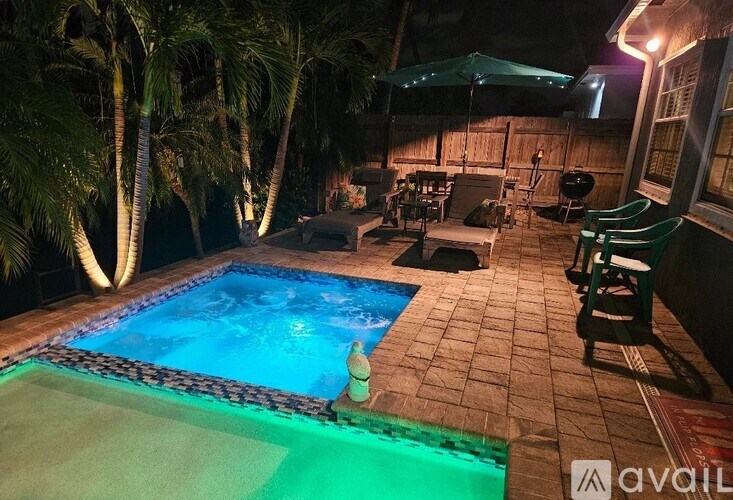 A pool surrounded by palm trees at night.