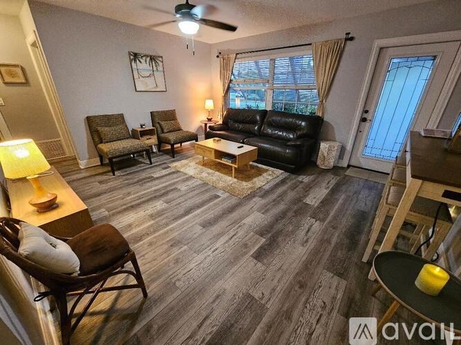 A living room with a black couch, a wooden coffee table, and a ceiling fan.