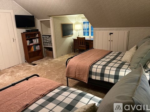 A bedroom with two beds and a television in the corner.