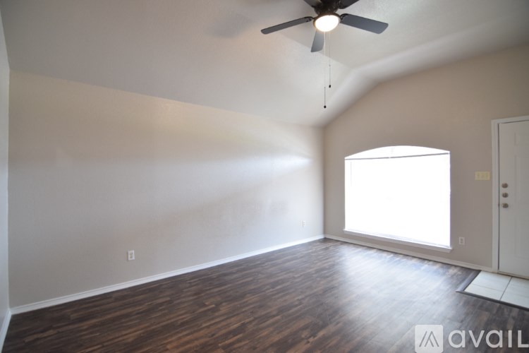 A room with a ceiling fan and wooden flooring.