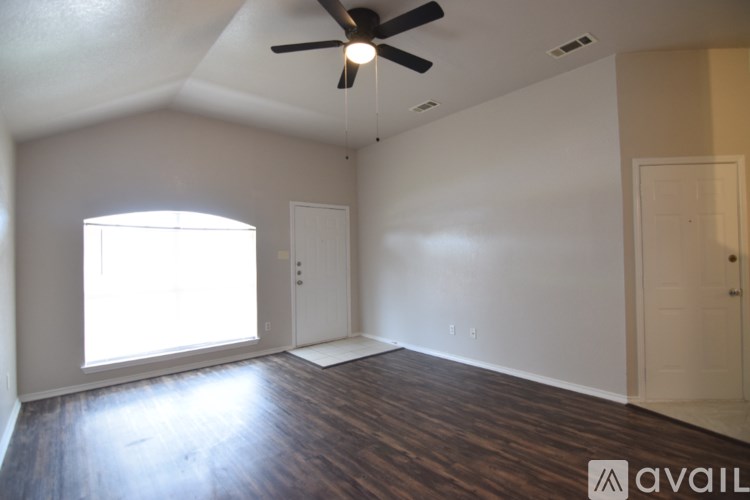 A room with a ceiling fan and wooden flooring.