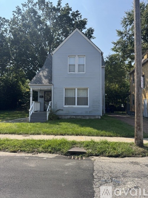 A small house with a grey roof and a white front porch.