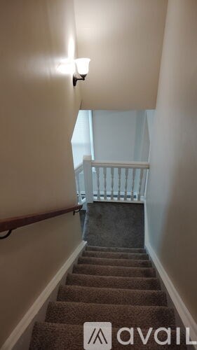 A staircase with a carpeted runner and a wooden handrail.