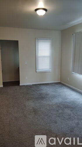 A room with a carpeted floor and a window with blinds.