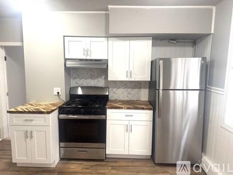 A kitchen with a stove top oven, a refrigerator, and cabinets.