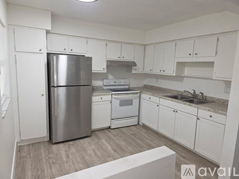 A kitchen with white cabinets and a stainless steel refrigerator.