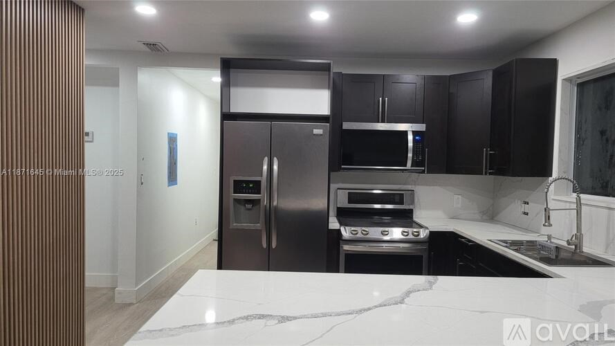 A modern kitchen with a refrigerator, oven, and microwave.