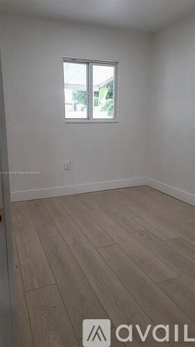 A room with a window and wooden flooring.