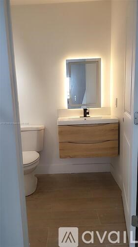 A bathroom with a toilet, sink and mirror.