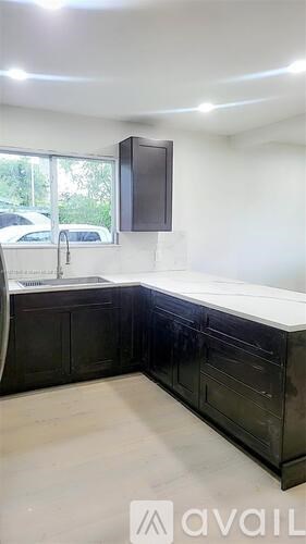 A kitchen with black cabinets and a white countertop.