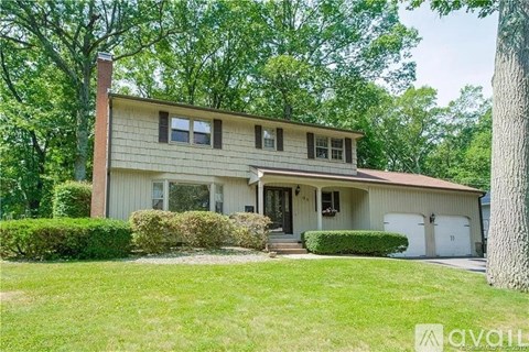 A house with a white garage door is surrounded by greenery.