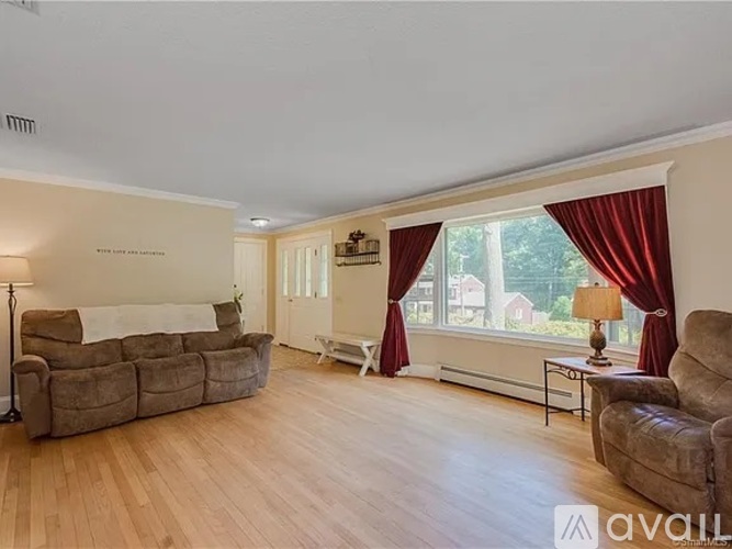 A living room with a brown couch and a white bed.