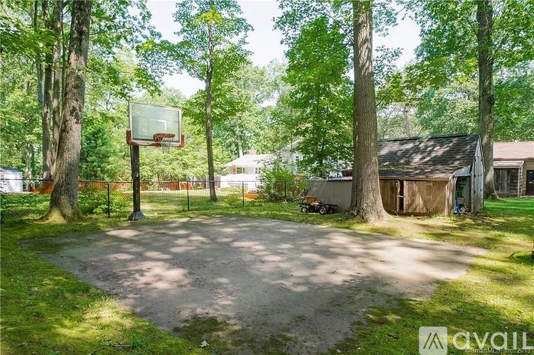 A basketball court surrounded by trees and a building in the background.
