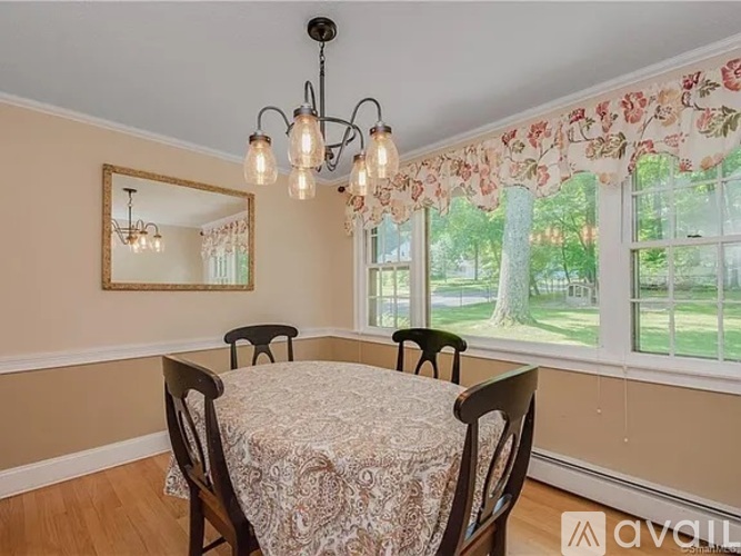 A dining room with a table and chairs and a window with a view of the outside.