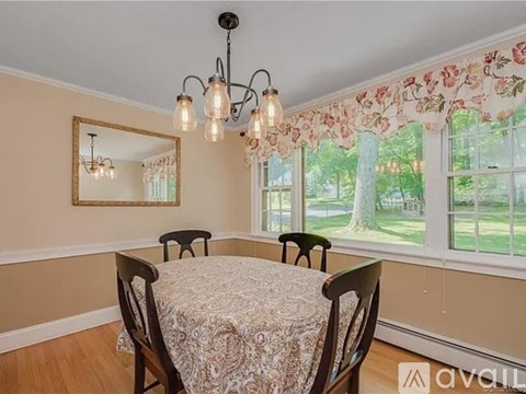 A dining room with a table and chairs and a window with a view of the outside.