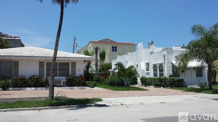 A white house with a palm tree in front.