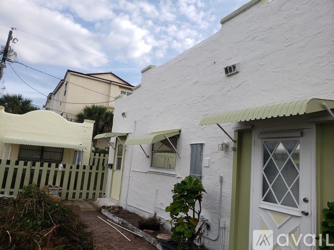 A white house with a green door and a small garden in front.
