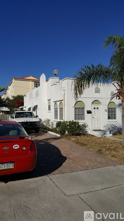 A red car is parked in front of a white building.
