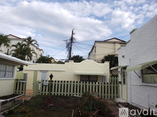 A white house with a green fence in front of it.