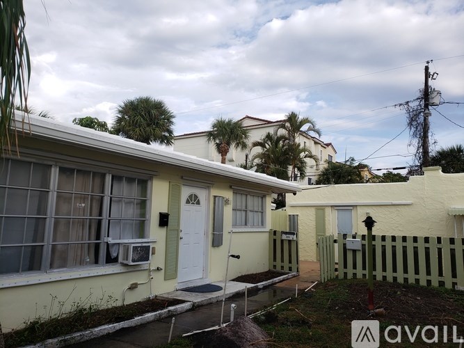 A house with a white door and a green fence is for sale.
