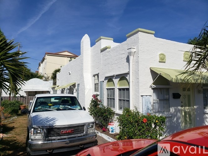 A white house with a red car parked in front.