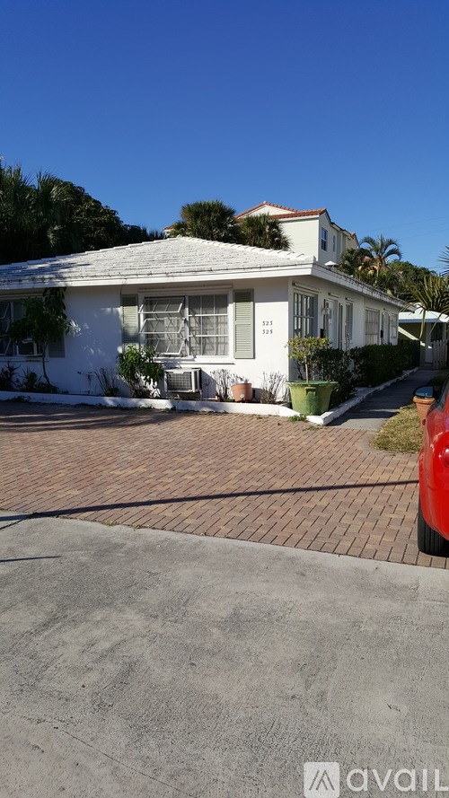 A white house with a red car parked in front.