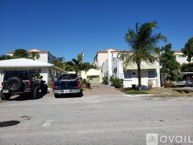 Two cars parked in front of a house with a palm tree.