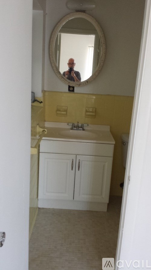 A bathroom with a round mirror and a sink with a cabinet underneath it.