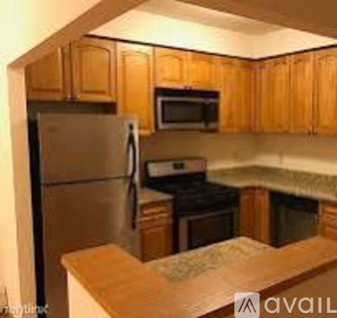 A kitchen with wooden cabinets and a stainless steel refrigerator.