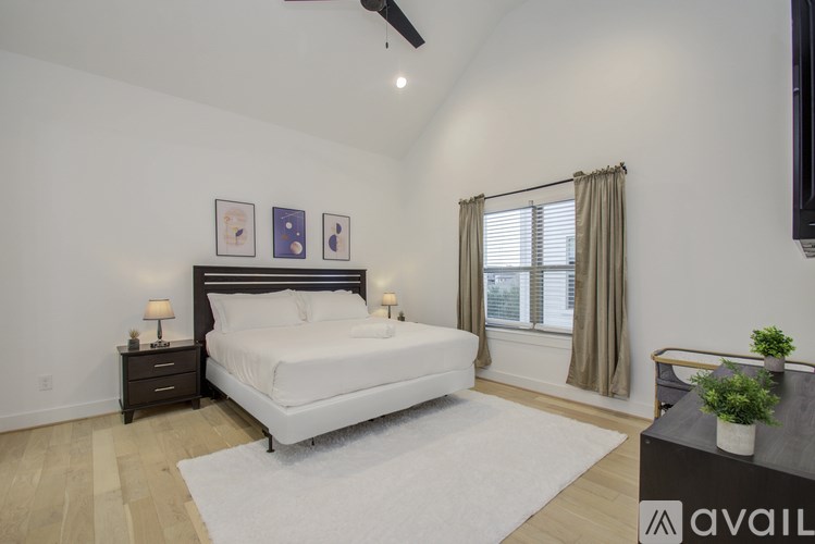 A bedroom with a large bed, a nightstand, and a window with curtains.