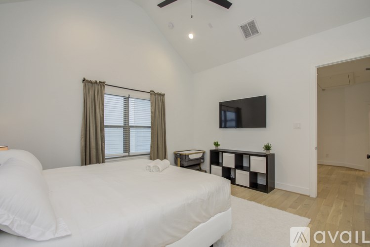 A bedroom with a large bed and a flat screen TV mounted on the wall.