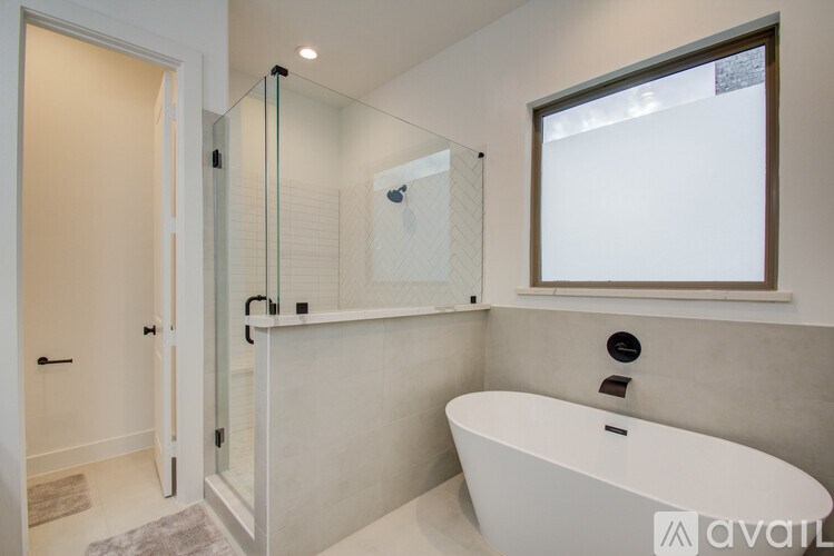 A modern bathroom with a white tub and a glass shower.
