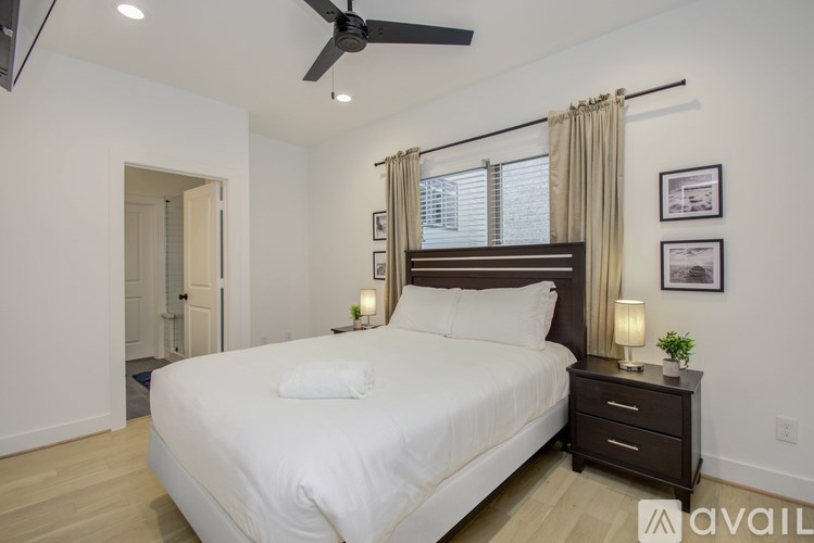 A bedroom with a large bed, a ceiling fan, and a window with curtains.