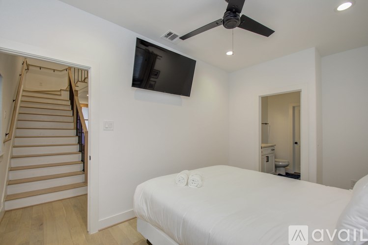 A bedroom with a bed, a television, and a staircase.