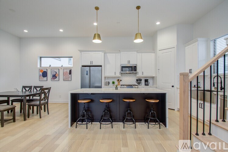 A kitchen with white cabinets and a bar area with stools.