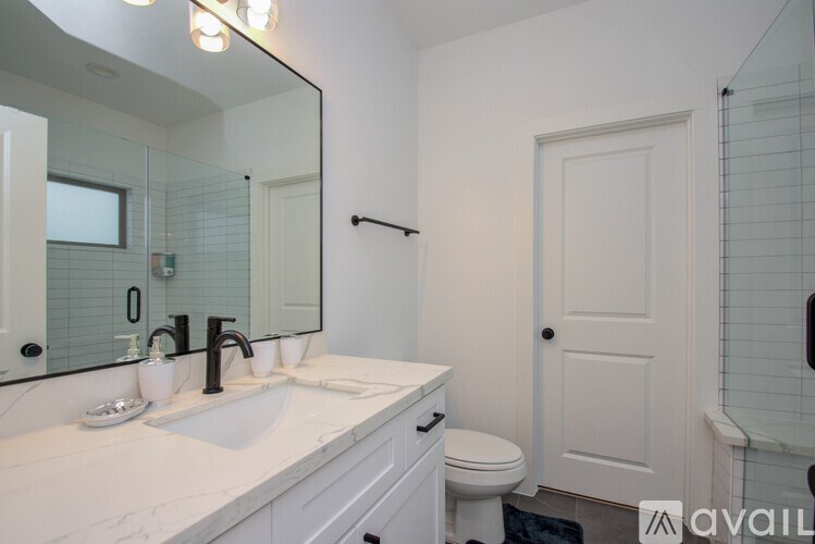 A bathroom with a sink, toilet, and mirror.
