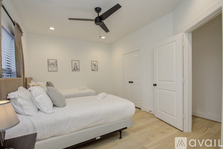 A bedroom with a bed, a ceiling fan, and two pictures on the wall.