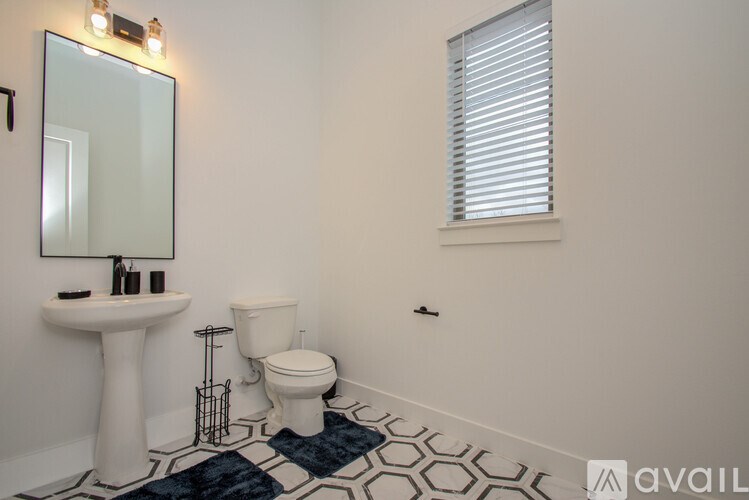 A bathroom with a white pedestal sink, toilet, and a mirror above it.