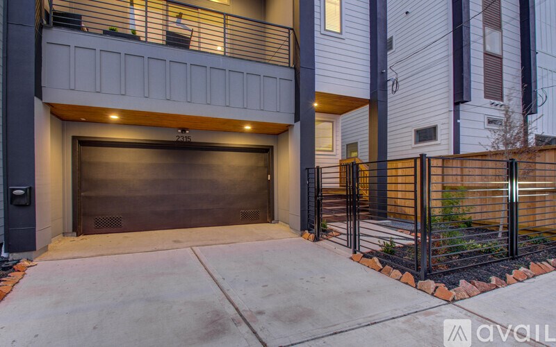 A modern garage door is closed and the wall is white.