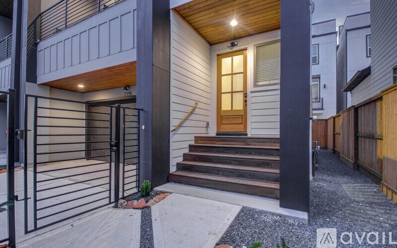 A modern house entrance with a wooden door and steps leading up to it.