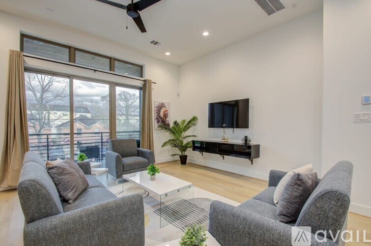 A living room with grey couches, a glass coffee table, and a flat screen TV.