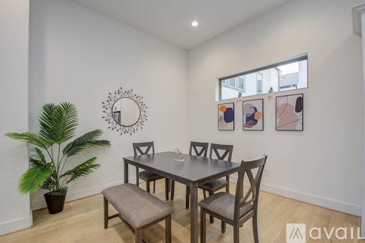 A dining room with a table set for four and a potted plant.