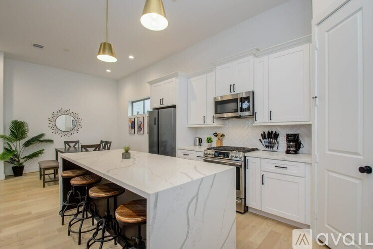 A modern kitchen with white cabinets and a marble island.