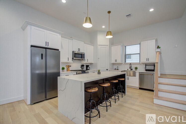 A kitchen with a marble island and stools.