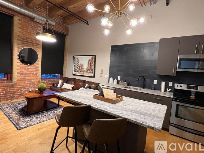 A modern kitchen with a brick wall and a dining table with chairs.