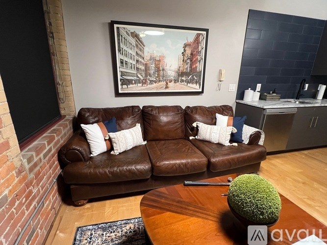 A brown leather couch with a green plant on a wooden table.