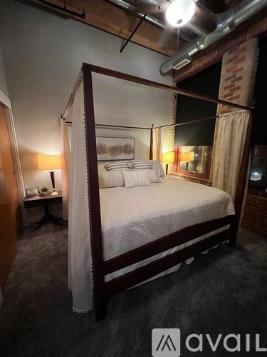 A bed with a white bedspread and a canopy is in the image.