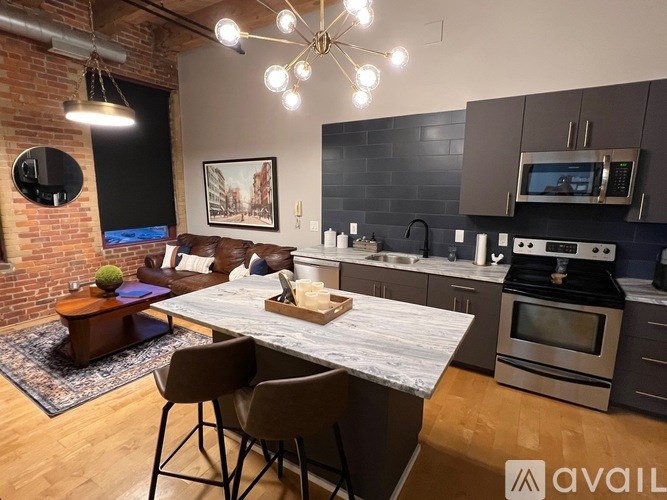 A modern kitchen with a brick wall and a dining table with chairs.