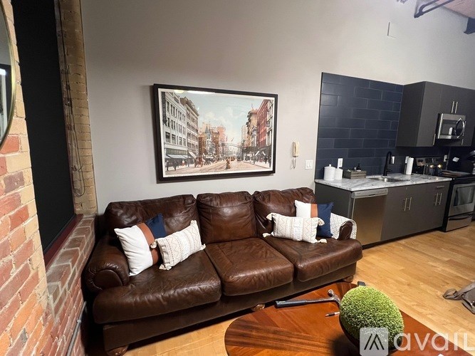 A brown leather couch with a green plant on a wooden table in front of it.