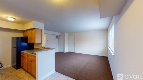 A kitchen with a refrigerator, cabinets, and a countertop is available for rent.